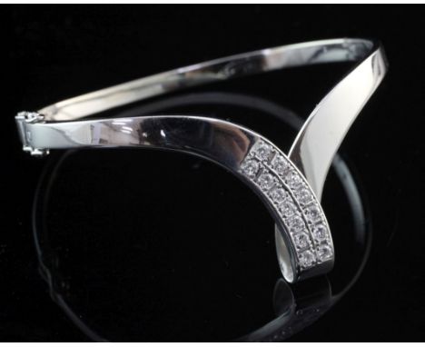 A 14ct white gold and diamond herringbone shaped hinged bangle, set with fourteen round cut diamonds.