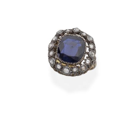 SAPPHIRE AND DIAMOND RINGThe cushion-shaped sapphire within an openwork foliate mount, set with cushion-shaped diamonds, betw