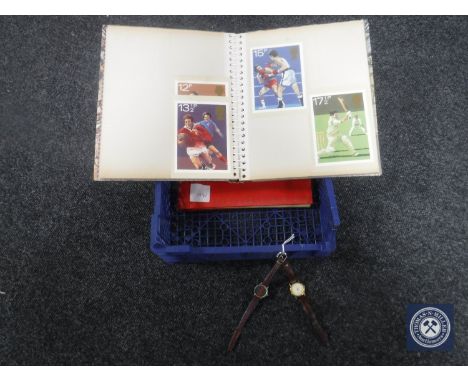 A crate containing two albums of first day covers together with two wristwatches 