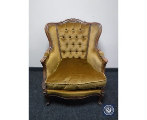 A 20th century carved wood framed armchair in gold button fabric 