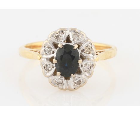 SOLD WITHOUT BUYERS PREMIUM AND VAT. An 18ct yellow gold sapphire and diamond cluster ring, set with a central oval cut sapph