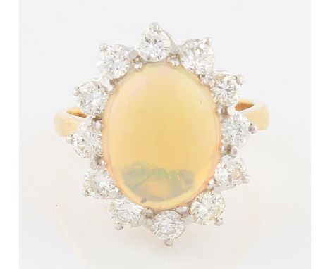 An opal and diamond cluster ring, set with a central oval opal cabochon, measuring approx. 14x10mm, surrounded by a border of