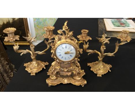 A 20th Century gilt mantel clock garniture, each having ornate foliage and screool design, the off-white coloured dial having