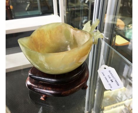 A carved jade bowl in the form of a fruit on carved wooden stand.