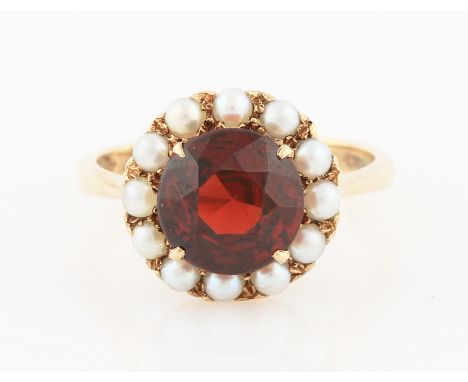 SOLD WITHOUT BUYERS PREMIUM AND VAT. A 9ct yellow gold garnet and seed pearl cluster ring, set with a central round cut garne