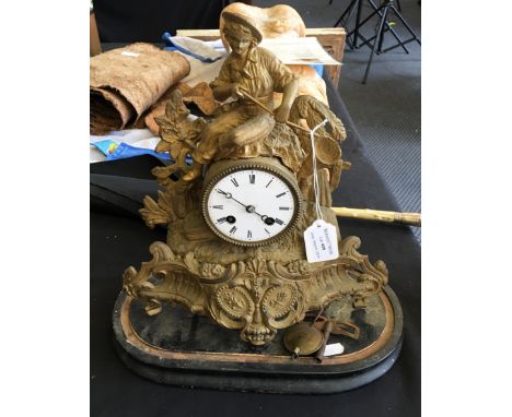 An early 20th Century brass clock with figural and ornate design body, having circular white enamel dial with black Roman num