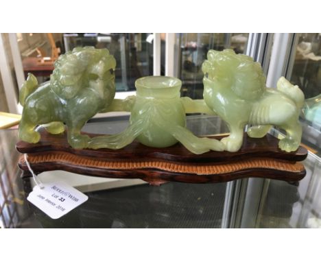 A carved jade sculpture depicting two mythical dogs with pot to centre, all on carved wooden base.