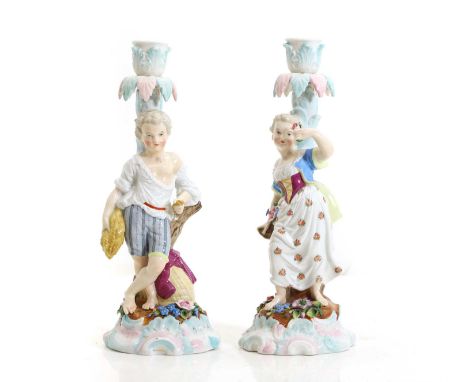 A pair of Dresden porcelain candlesticks the leaf decorated sconces on figural supports and flower detailed bases26cm highCon