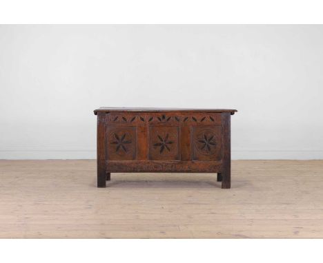 A small oak coffer, 17th century, the plank top over a three-panelled front, with carved and inlaid geometric decoration and 