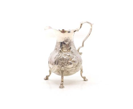 A George III silver cream jug, marks worn, embossed and chased with a squirrel holding a nut, verso, a panel of fruit, 10.5cm