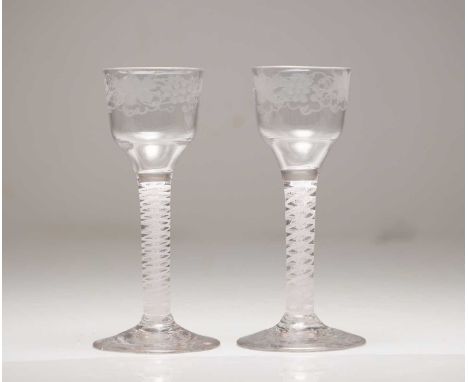 A pair of wine glasses c.1765, each with an ogee bowl engraved with fruiting vine, over a double series opaque twist stem and