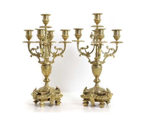 A pair of gilt metal candelabra late 19th century, the urn form column fitted central sconce encompassed by four fuller sconc