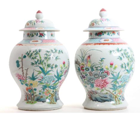 A pair of Chinese famille rose vases and covers, 20th century, of baluster form, painted with a bird perched on a blossoming 