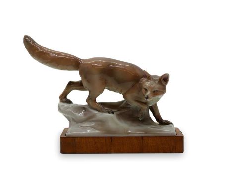 A German porcelain model of a fox, on a walnut base, 39cm wideCondition Reportveneer flaking to the front, cracks.