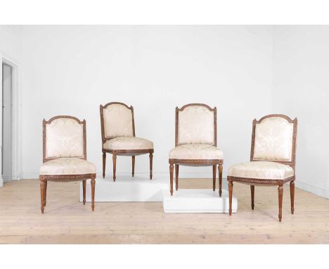 A set of four Louis XVI-style walnut and parcel-gilt side chairs, late 19th/early 20th century, French, each with an arched b