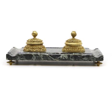 A gilt bronze and marble inkstand, each inkwell, with a hinged cover and glass liner, raised on low feet, 35cm wide 19cm deep