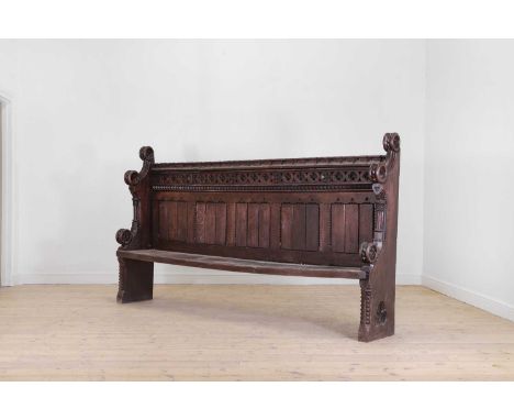 A carved oak pew, 19th century, with a crenulated top rail, over a pierced quatrefoil frieze and panels, the sides with carve