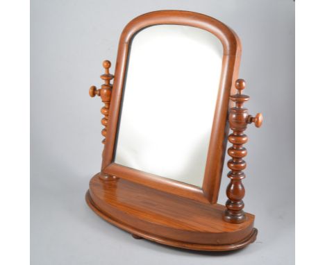A mahogany framed swing toilet mirror, domed top with bobbin turned supports on a bow fronted base, overall 50cm high.