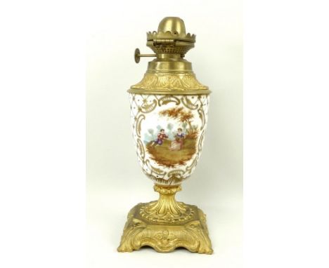 A ceramic and brass oil lamp, the ceramic body with hand painted reserves of musicians and flowers, with diaper gilding, on c