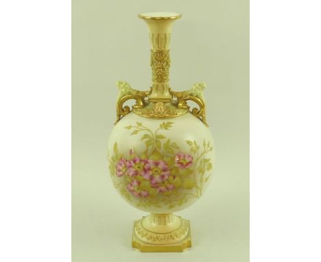 A Royal Worcester blush ivory bottle vase with dogs head moulded masks to the scrolled handles and Green man mask to the coll