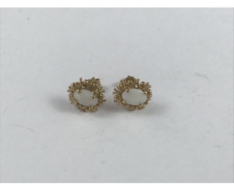 A pair of opal and 9ct gold stud earrings, the oval cabochons being claw-set within pelleted C-scroll frames