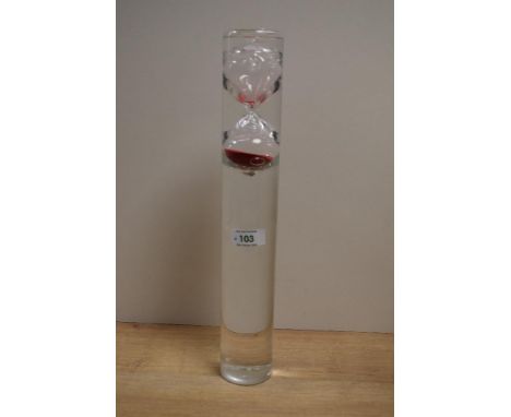 A modern clear glass and red sand egg timer, encased in a water filled clear glass cylinder, when turned upside down the time