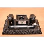 An Indian ebonised desk stand, having a central inkwell flanked by two moulded elephants and