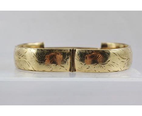 A 9CT GOLD BANGLE, having floral engraved decoration 