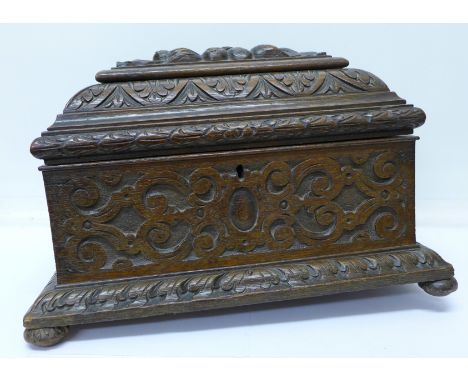 A carved oak tea caddy with compartment in lid, one bun foot lacking, no interior fittings but with some loose parts, width 3