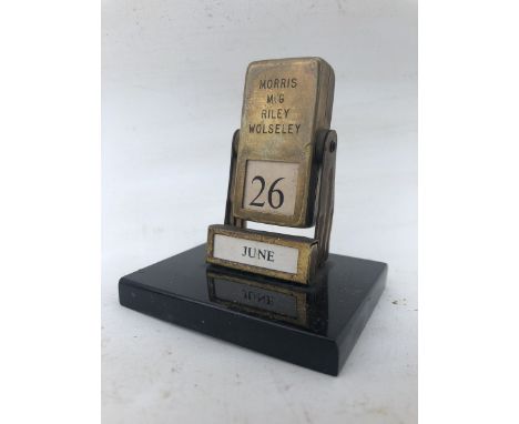 A brass desktop calendar engraved with the car manufacturers Morris, MG, Riley and Wolseley.