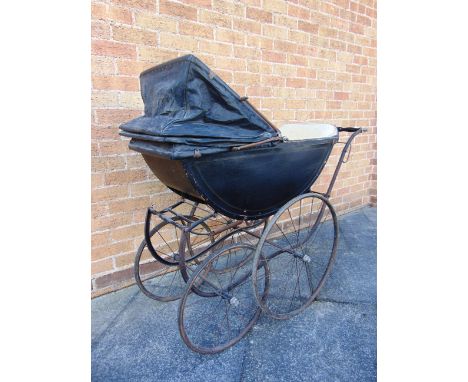 A BABY'S PRAM  the lined black wood body with a folding rexine hood, and a cream padded interior, the base with a lift-out ce