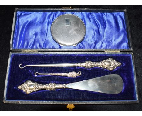 A SILVER LADIES COMPACT  together with a cased set of silver topped implements (shoe horn, button hook and miniature button h