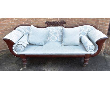 A REGENCY STYLE CARVED MAHOGANY FRAMED SOFA  with scroll arms, loose squab and pair of bolster cushions, on turned supports w