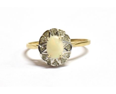 A 9CT GOLD WHITE OPAL FLOWER HEAD RING The oval white opal sat in a bed of clear gem flecked white metal on a yellow gold sha