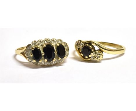 TWO 9CT GOLD SAPPHIRE RINGS Comprising a three stone cluster ring and a single stone cross over ring both with 375 faded hall