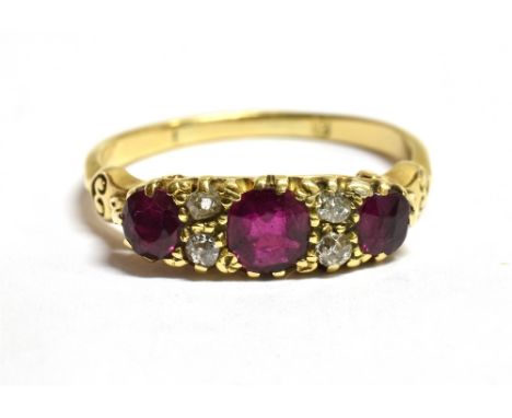 A DIAMOND AND RUBY DRESS RING The ring set with three rubies spaced with a pair of small diamonds each side of the central ru