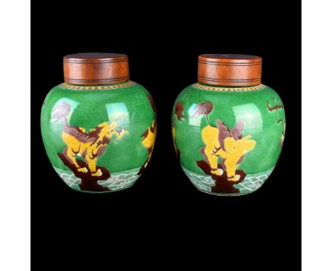 Pair Chinese Pottery Ginger Jars. Glazed motif of Foo Dogs on green ground. Wood lids. Incised marks on bottom. Measures 8-1/