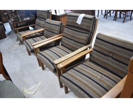 Three vintage teak framed easy chairs, with upholstery label for Ercol , and a similar rocking chair
