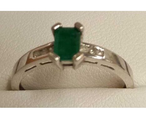 AN EMERALD RING WITH DIAMOND SHOULDERS SET IN 18ct WHITE GOLD