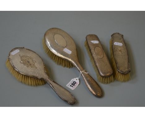 TWO SILVER BACKED PART DRESSING TABLE SETS, hammered and engine turned decoration, various dates and makers (4)