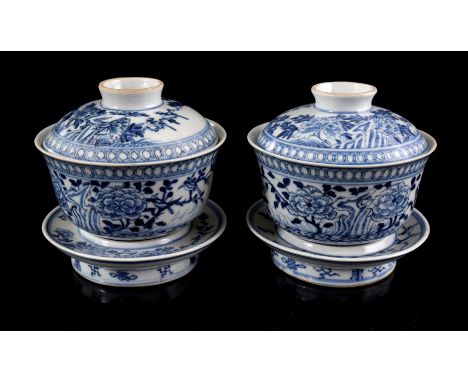 2 porcelain lidded bowls on stands with blue and white floral decor near the rock and Chinese characters and Taoist symbols, 