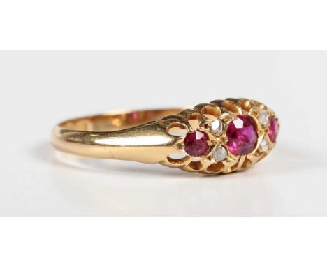 An Edwardian 18ct gold, ruby and diamond ring, mounted with three cushion shaped rubies with two pairs of rose cut diamonds a