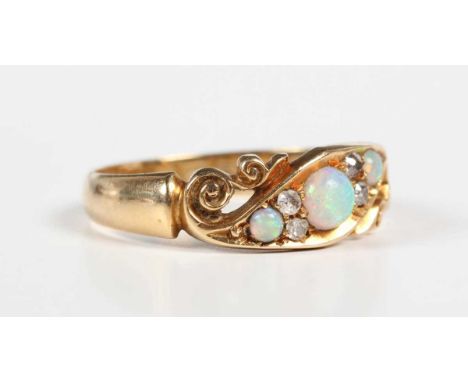 An Edwardian 18ct gold, opal and diamond ring, mounted with three opals and two pairs of old cut diamonds in a scroll design,