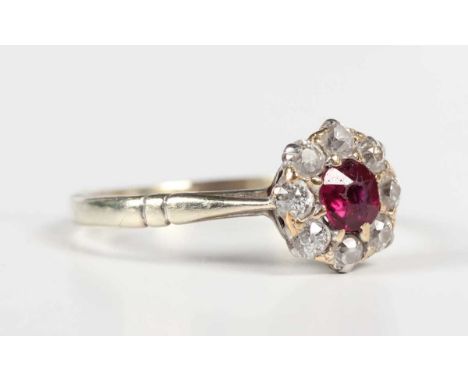 A gold, ruby and diamond cluster ring, claw set with the cushion cut ruby within a surround of eight old cut diamonds, unmark