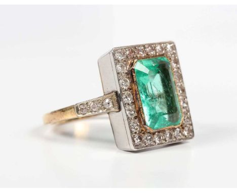 A gold, emerald and diamond rectangular cluster ring, collet set with the cut cornered rectangular step cut emerald within a 