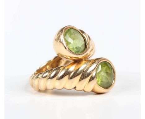 A gold and peridot two stone ring in a crossover design with ridged decoration, detailed ‘750 Verdura’, weight 13.2g, ring si