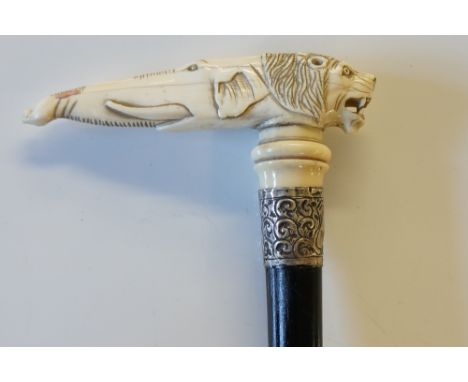 A late 19th Century ivory handled walking stick, the handle carved with snarling lion's head at front and elephant's head at 