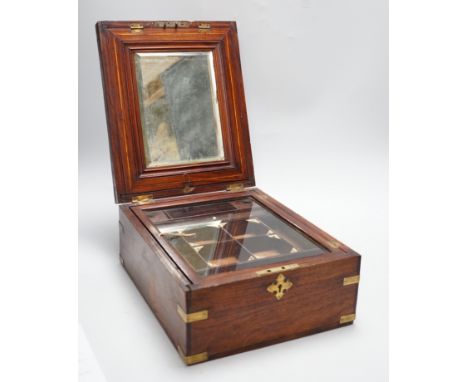 An Anglo-Indian wooden brass bound sewing box, with fitted interior and removable sections, hinged bevelled mirror, internal 