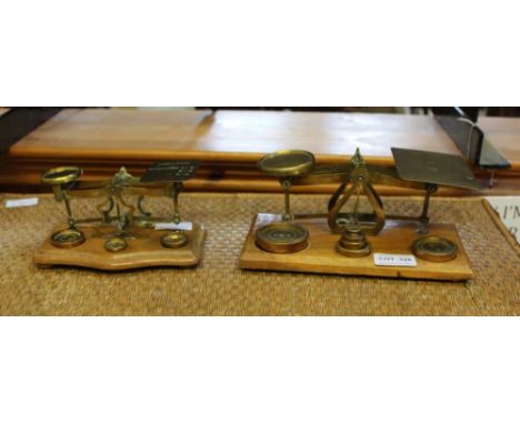 TWO SETS OF BRASS POSTAL SCALES with weights on wooden plinth bases 