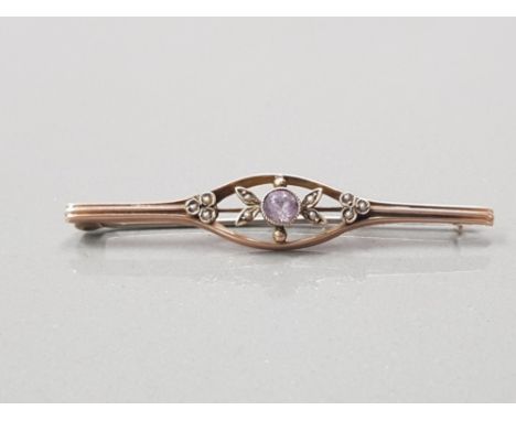 9CT YELLOW GOLD BROOCH FULLY HALLMARKED TH+CO BIRMINGHAM 1913 THE OVOID CENTRE SET WITH FACETED AMETHYST FLANKED BY FLOWERS A